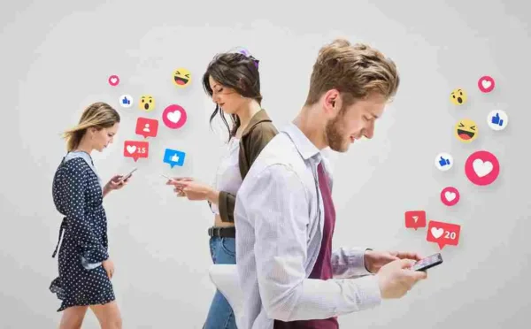 A imagem mostra três pessoas usando smartphones, com ícones de redes sociais e interações ao redor, simbolizando a influência e o uso do marketing digital. No contexto do artigo, isso reflete a importância de integrar estratégias digitais em campanhas de varejo para alcançar e engajar os clientes, utilizando plataformas sociais e ferramentas de marketing para aumentar a visibilidade e a conversão de vendas.