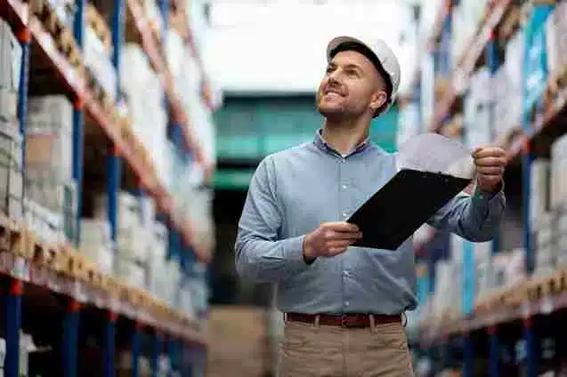 A imagem retrata um funcionário de um armazém ou depósito realizando o processo de picking, ou seja, a separação de itens para atender a um pedido. A imagem ilustra como a integração de sistemas ERP pode beneficiar o processo de picking em um ambiente de armazenagem, tornando-o mais eficiente e preciso.