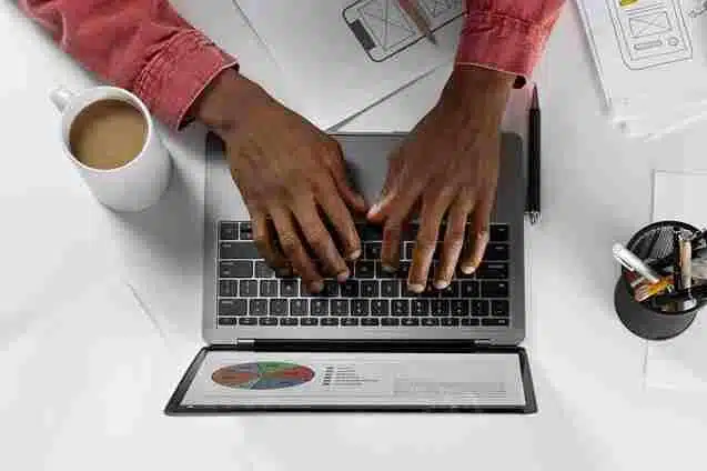 A imagem mostra um homem trabalhando em um computador, com gráficos e relatórios abertos na tela. Isso sugere que o artigo "SEO para e-commerce: melhore o seu ranqueamento no Google para ter mais vendas!" abordará estratégias de otimização de sites de comércio eletrônico para melhorar o posicionamento nos resultados de pesquisa do Google.