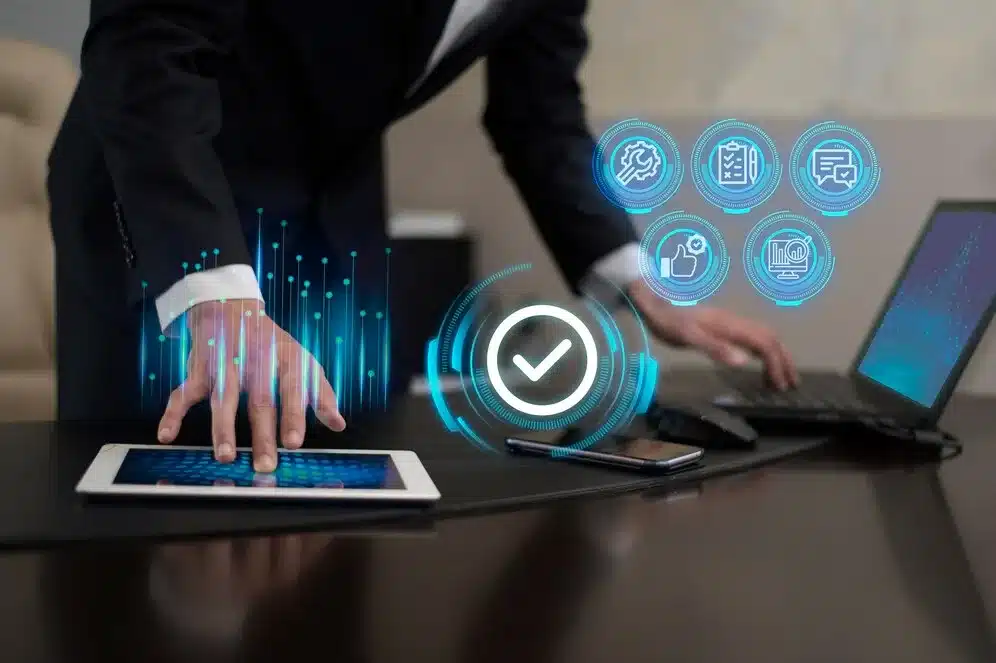 A imagem ilustra a automação de processos de negócios, sugerindo como um sistema ERP (Enterprise Resource Planning) pode integrar e otimizar as operações em um ambiente varejista. É mostrado um executivo interagindo com dispositivos digitais, com ícones de automação e verificação em volta, simbolizando a eficiência e a precisão que o ERP pode trazer para o gerenciamento de estoque, vendas e relatórios financeiros em lojas de varejo.
