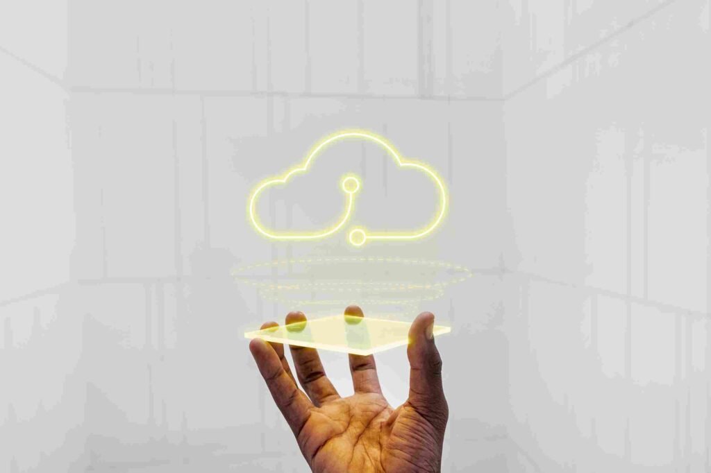 Mão segurando uma placa de vidro transparente que projeta um ícone de nuvem amarela brilhante em estilo neon. O fundo é minimalista e futurista em tons de cinza claro. A imagem simboliza a transição para o ERP na Nuvem (Cloud ERP) em 2026, destacando mobilidade, segurança de dados e a centralização da gestão empresarial digital.